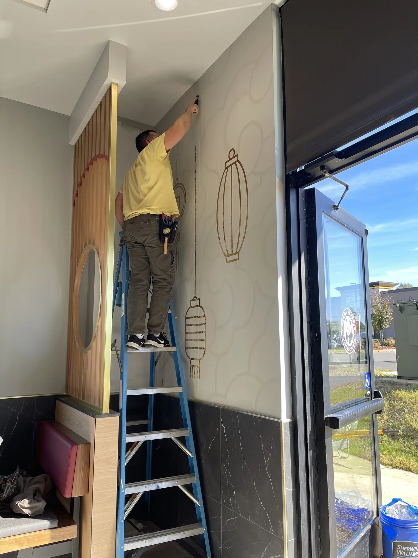 Wallpaper installer smoothing a panel from a ladder